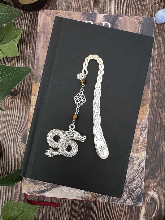 Marque-page en métal dragon oriental avec des pierres naturelles oeil-de-tigre. Les pierres sont personnalisables. Bellette Workshop. Metal bookmark with gemstones. posé sur un livre noir 