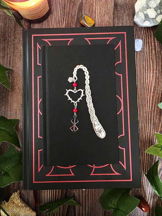 Marque-page dark fantasy en métal, orné d'un cœur d'épines, de la marque du sacrifice et de véritables pierres naturelles. Corail rouge sur le modèle. Inspiré par berserk. Fait main par bellette workshop