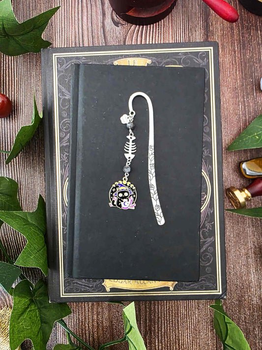 Ce marque-page en métal argenté est orné d'un petit chat noir sorcier, installé devant sa boule de cristal sous un ciel étoilé. Il est accompagné d'une breloque en forme d'arête de poisson et de véritables pierres naturelles de labradorite noire.
