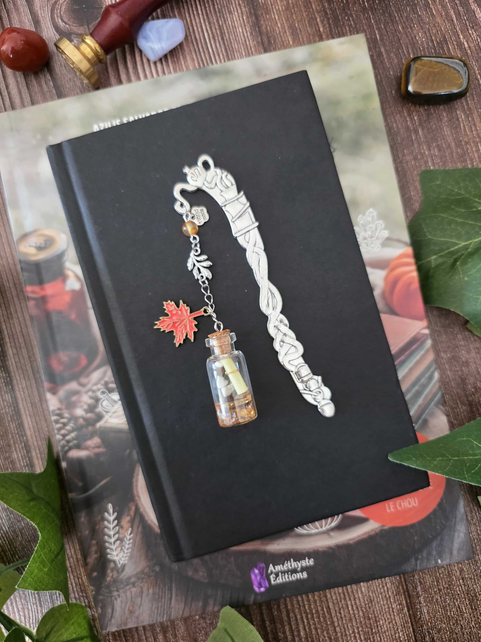 Ce marque-page en métal argenté est orné d’une véritable petite fiole d'automne en verre qui peut être ouverte. À l’intérieur se trouve un petit morceau de papier sur lequel vous pouvez écrire quelques mots