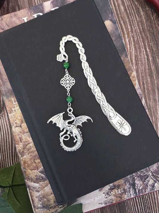 Marque-page en métal Dragon orné de pierres fines naturelles de jade, personnalisable. Le signet est posé sur un livre noir, un livre de Tolkien en dessous. 