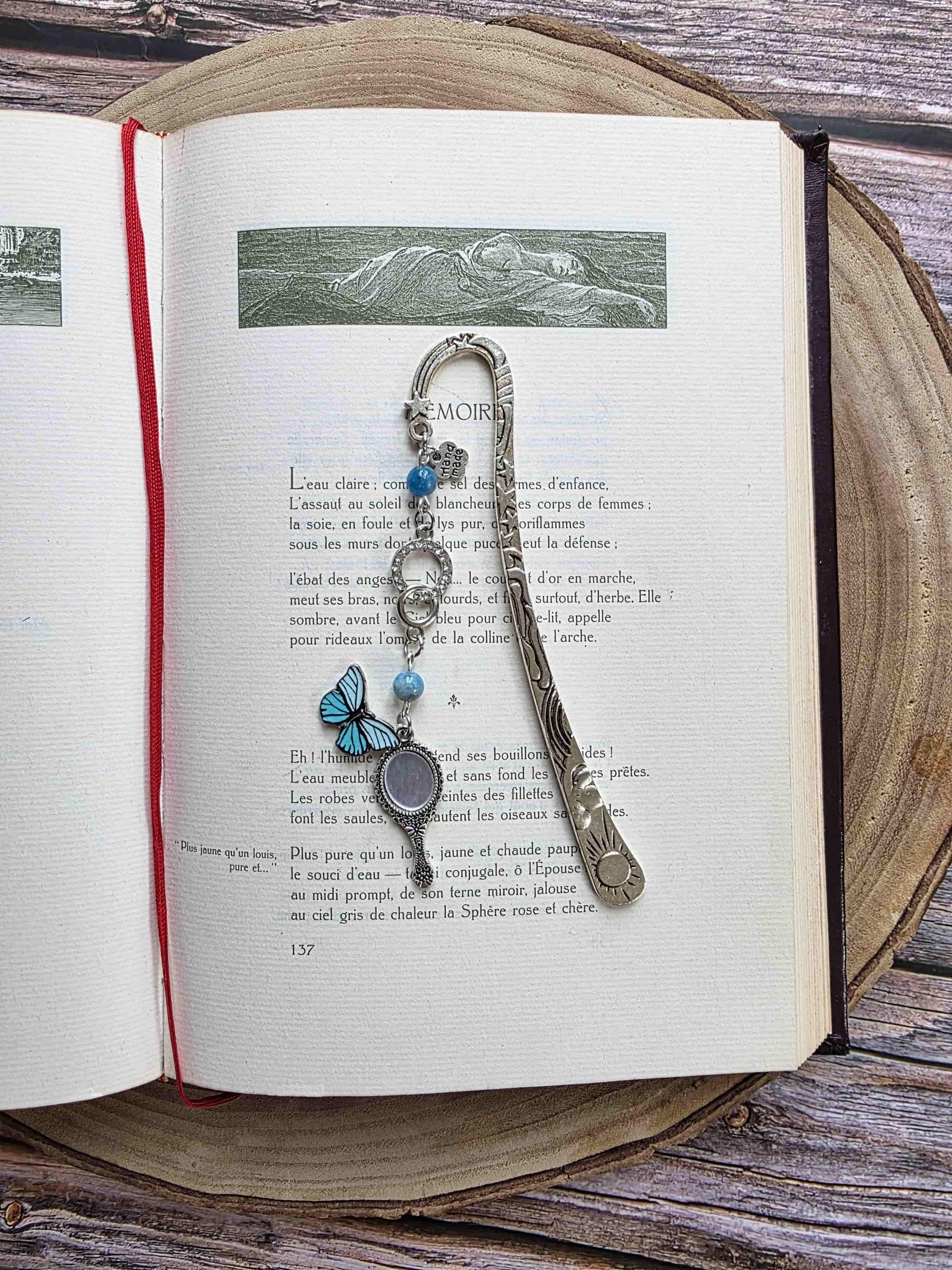 marque-page miroir enchanté, papillon bleu avec un ruban et deux pierres naturelles d'apatite bleue. Le signet est fait à la main par bellette workshop. Ce bijou de lecture est personnalisable. vu dans les pages d'un livre